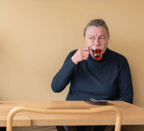 Senior woman having tea with a peach background