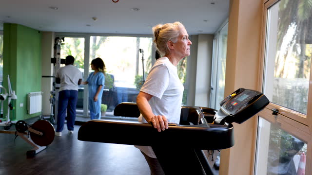 Senior woman doing physical therapy at a rehabilitation center and walking on a treadmill