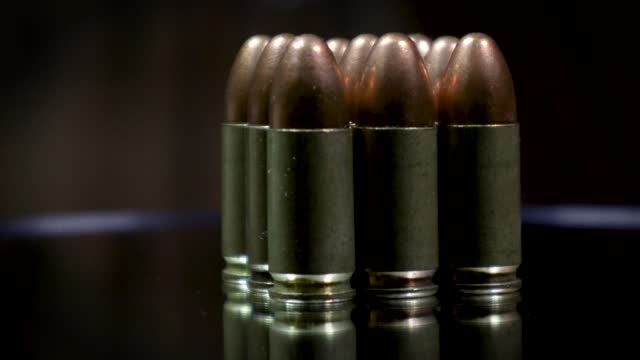 A closeup of a stack of 9mm bullets with reflection on the glass plate of the rotating table.