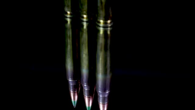 5.56 caliber bullets rotating with their reflection on a glass plate with their reflection