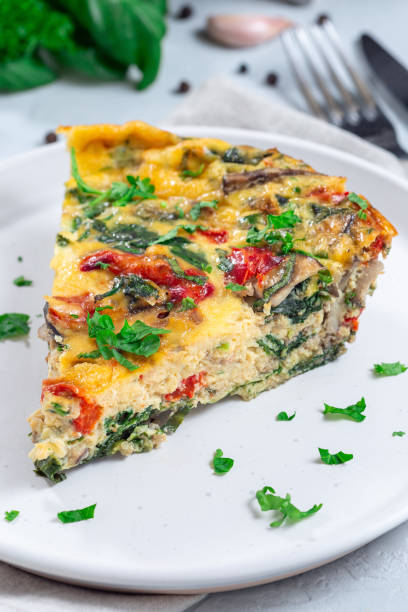 istock Piece of brunch egg frittata with vegetables on plate, vertical, closeup 1972990059