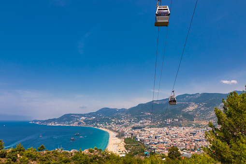 Alanya Teleferik (Cable Car) cabins ascending above the city, offering stunning views of the coast and Kleopatra Beach in Alanya, Turkey