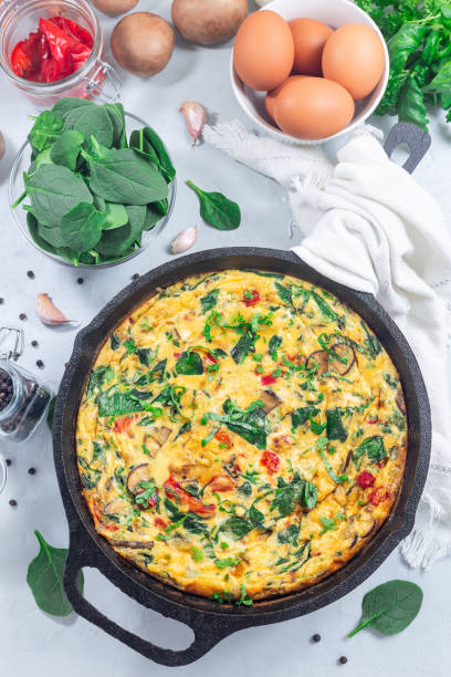 istock Brunch egg frittata with spinach, roasted red peppers, mushrooms, in cast iron, vertical, top view 1973001217
