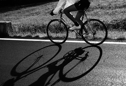 shadow of the cyclist on the racing bike on the road in backlight with very dark and dramatic tones effect ideal as a background for sports concept