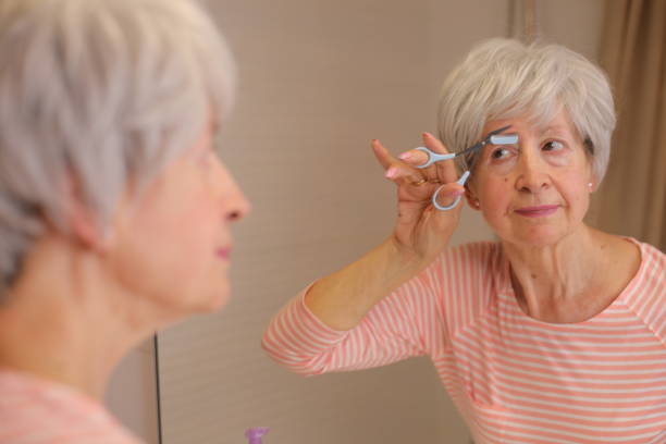 istock Senior woman cutting her eyebrows with precision scissors 1973004564