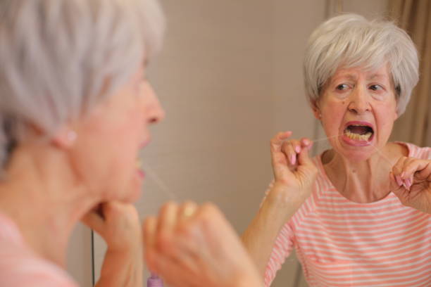 istock Senior woman presenting difficulties to floss her teeth 1973018932