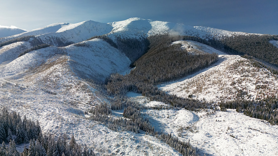 Aerial view of Low Tatras mountains, Slovakia in winter. Beautiful panoramic nature landscape with high rocks, forest of pine and fir trees in cold weather, countryside scenery in frozen season
