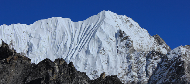 Blue sky over a high snow covered mountain in the Himalayas, view from Gorakshep, Nepal.