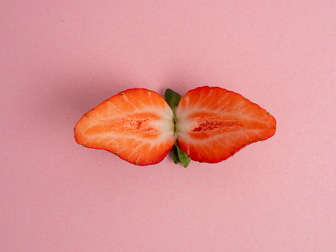Strawberries cut in half on a pink background. Strawberries close up.