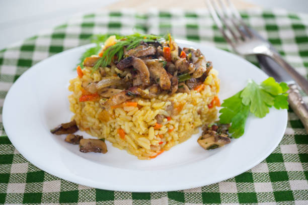 Diet pilaf with mushrooms and vegetables in a plate on a light wooden table. Vegetarian food.