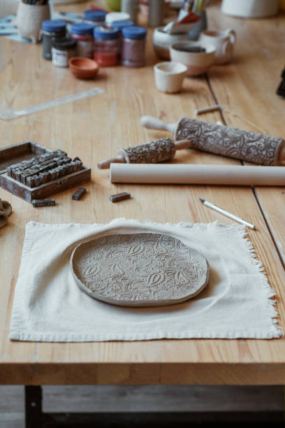 istock Beautiful raw clay plate with ornament on table in workshop 1973069049