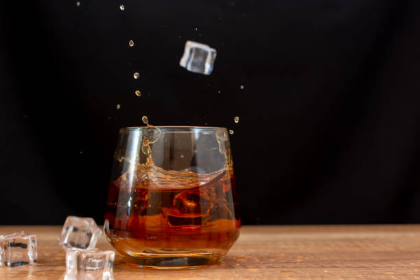 ウイスキーのグラスに落ちる角氷 - whisky glass ice cube alcohol ストックフォトと画像