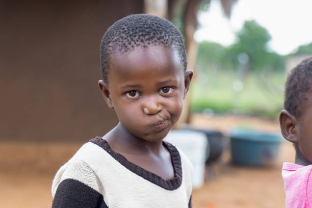istock village african child, standing in the yard , playing pulling faces, skew mouth 1973069667