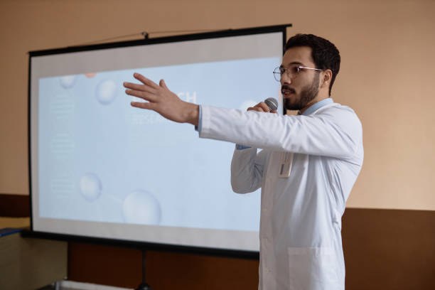 istock Male Doctor Speaking into Microphone at Presentation 1973072718