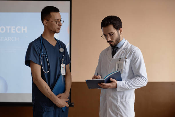 istock Male Medical Presentation Speaker Writing down Colleagues Questions 1973072740