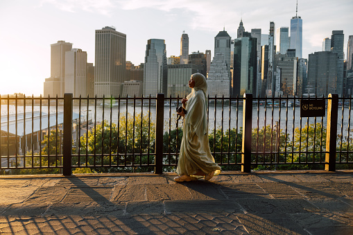 Woman walks in Brooklyn Heights with New York cityscape on the background.