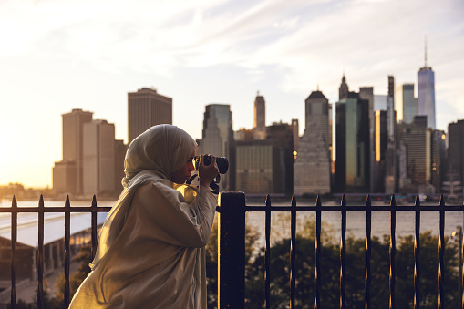 Woman walks in Brooklyn Heights with New York cityscape on the background.