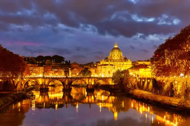 Photo of Beautiful vibrant night image of St. Peter's Basilica, Ponte Sant Angelo and Tiber River at dusk in Rome, Italy.