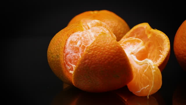 ripe tangerines with peel on black background