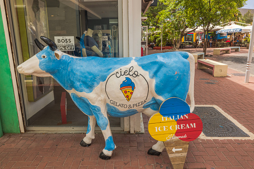 CurstatueWillemstad. 01.30.2024. A statue of a white-and-blue cow near an ice cream shop window in downtown Willemstad.