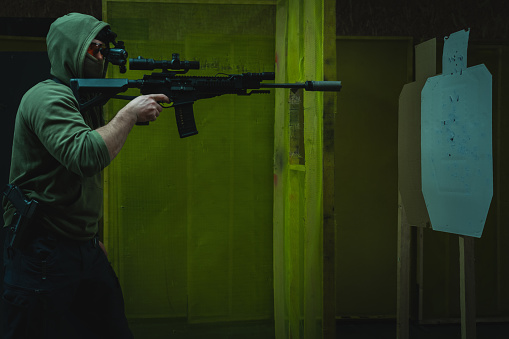 A man engages in tactical rifle shooting with nightvision at a shooting range in dark. . High quality photo