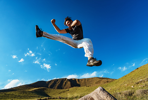 Handsome athletic young man jumping on mountains background