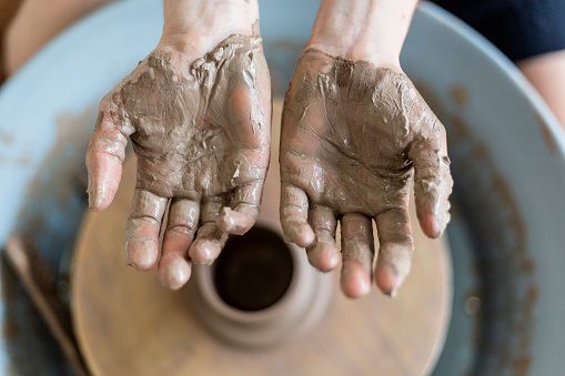 Women's hands dirty with clay on ceramics