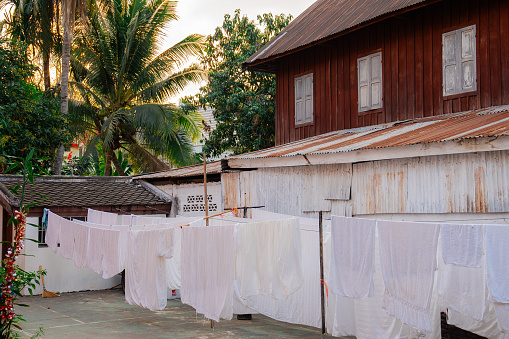 White sheets drying on wind on rope near the asian house