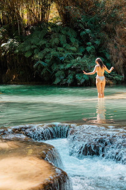istock Woman in swimsuit  enjoys refreshing  waterfall in tropical forest 1973155115