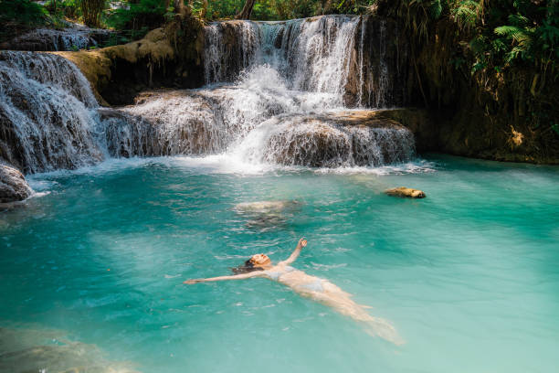 Young Caucasian woman near the  Kuang si waterfall in tropical forest in Southeast Asia, Laos