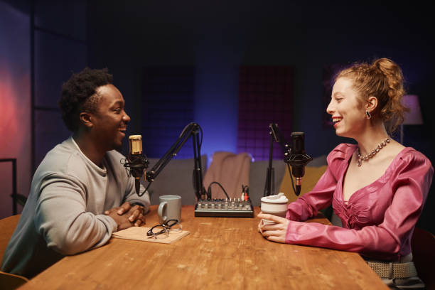 istock Two Diverse Laughing Bloggers in Podcast Room 1973173253