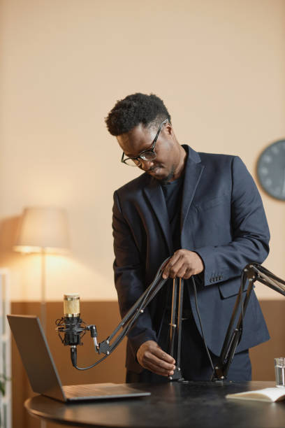 istock Male Podcaster Fixing Microphone on Stand 1973173277