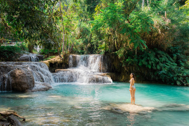 istock Woman in swimsuit  enjoys refreshing  waterfall in tropical forest 1973191449