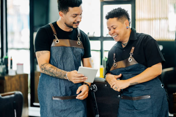 istock Two barbers looking at haircut ideas on digital tablet in barbershop 1973191971