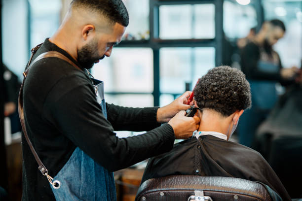 barbiere che taglia i capelli di un giovane cliente nel suo negozio di barbiere - make over series foto e immagini stock