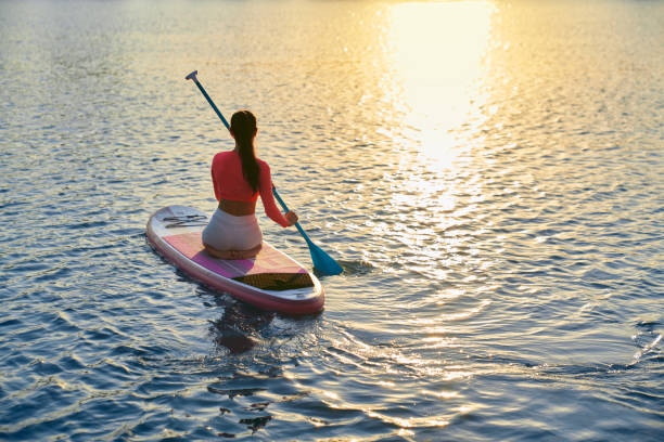 istock Healthy woman sitting on sup board and rowing with paddle 1973193577