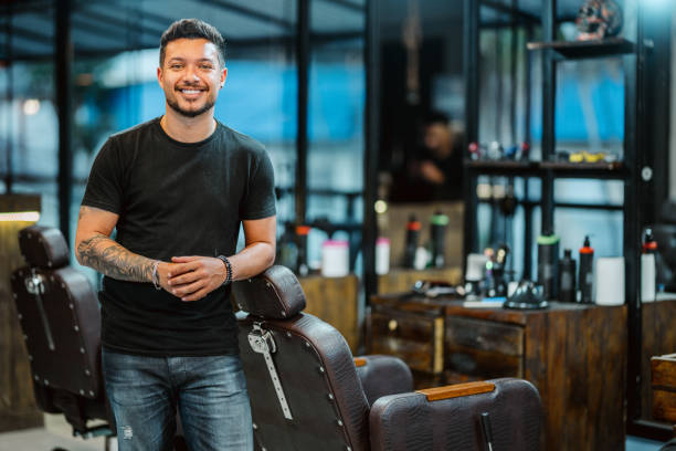 istock Smiling barber leaning on a chair while working in a barber shop 1973194672