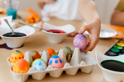 Children hands dying Easter eggs at the table at home and having fun