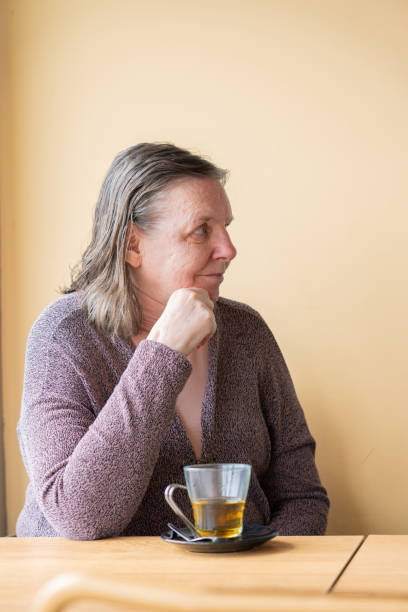 istock Mature woman having tea with a peach wall behind 1973211045