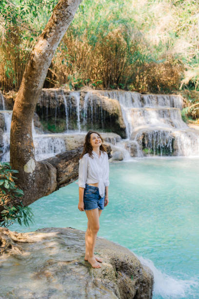 istock Woman enjoys refreshing  waterfall in tropical forest 1973213131