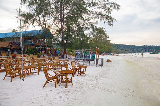 Koh Rong Sanloem, Cambodia, April 27 2019: Serene sunset scene at a tropical beach resort with dining chairs on the sand