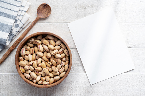 Empty recipe card mockup and bowl of pistachios. Handmade from walnut wood with spoon