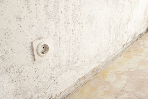 Detail of an electric outlet on a damaged wall and floor ready to be restored. Home renovation concept
