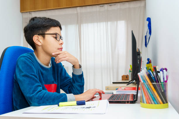 istock A highly focused preteen demonstrates his dedication to education while using his laptop to do his homework 1973237080