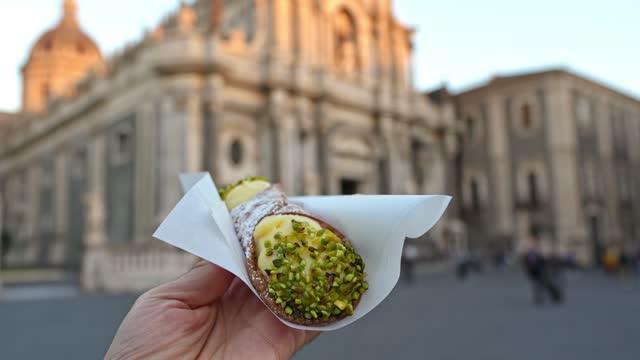 Man Eating Cannoli Pastry Filled With Creamy Ricotta And Pistachios On The Street In Catania, Sicily