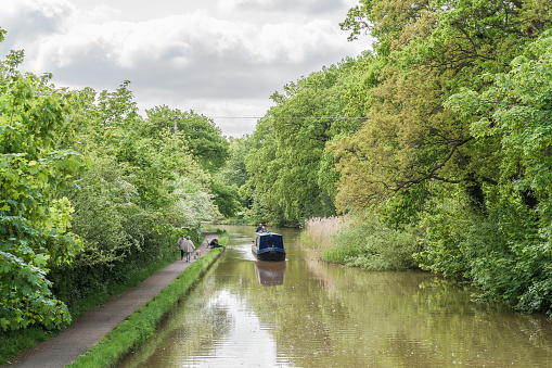 Nantwich, Cheshire East, England, June 6th 2023. Vintage narrowboat on canal, transport, travel and tourism concept illustration.