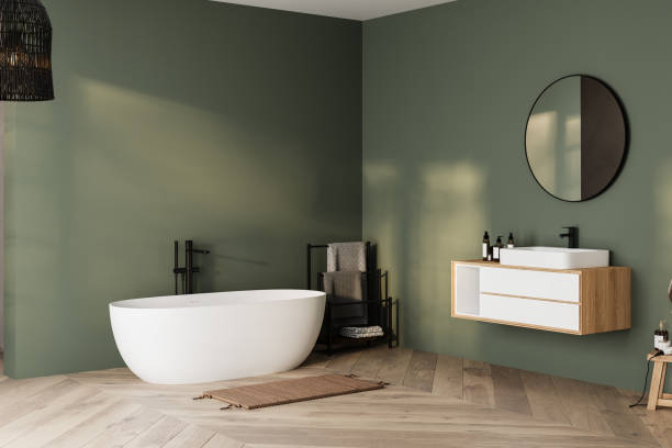 istock Modern minimalist bathroom interior, bathtub and bathroom cabinet, white sink, interior plants, bathroom accessories, parquet floor, green wall. 1973272824