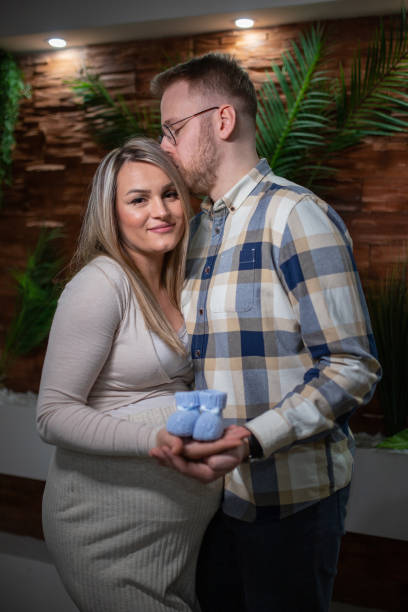 happy pregnant woman and her husband holding baby shoes - human pregnancy couple prenatal care heterosexual couple imagens e fotografias de stock