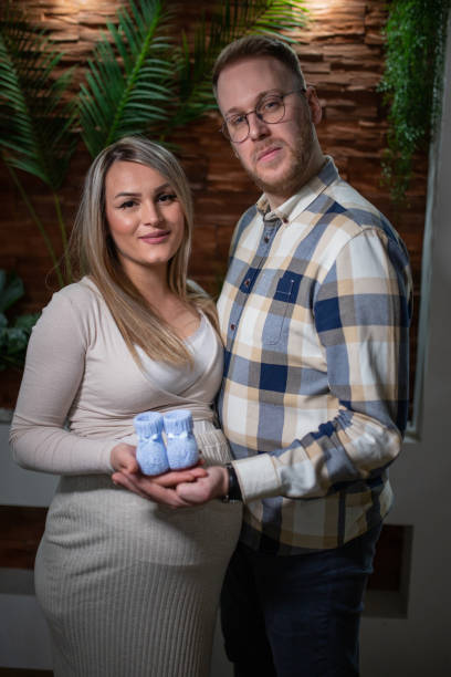 happy pregnant woman and her husband holding baby shoes - human pregnancy couple prenatal care heterosexual couple imagens e fotografias de stock