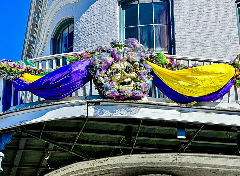 Mardi Gras mask decorations on building in the french quarter New Orleans Louisiana. Special gold and purple draped fabrics for carnival celebration.